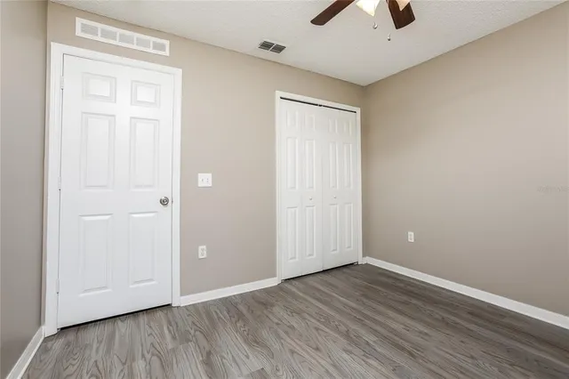 an empty room with wooden floor and a ceiling fan