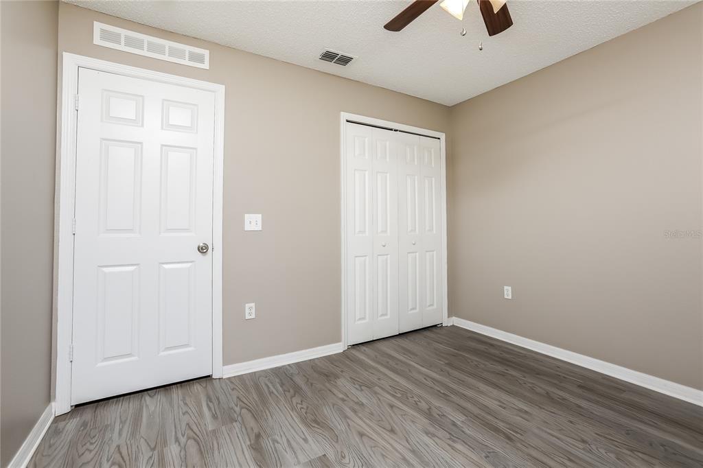 977 Vanderbilt Drive Eustis, FL 32726 - Photo 10 of 16 an empty room with wooden floor and a ceiling fan