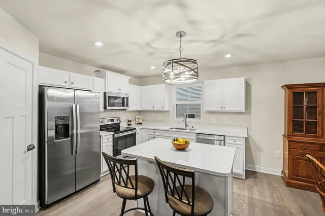 a kitchen with stainless steel appliances a dining table chairs refrigerator and stove