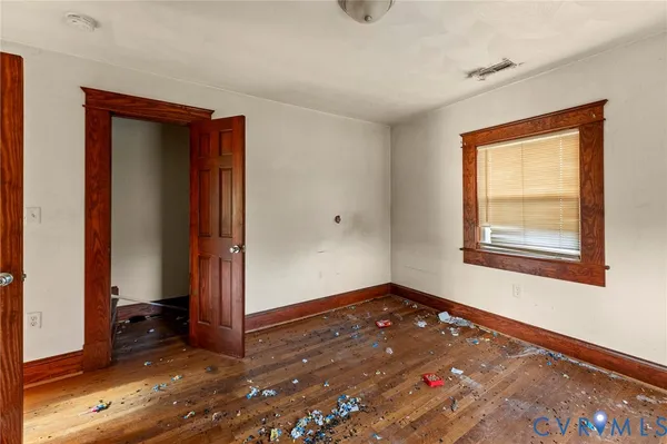 a view of an empty room with window and wooden floor