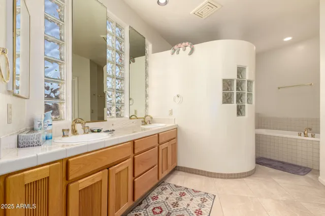 a bathroom with a double vanity sink a mirror and a bathtub