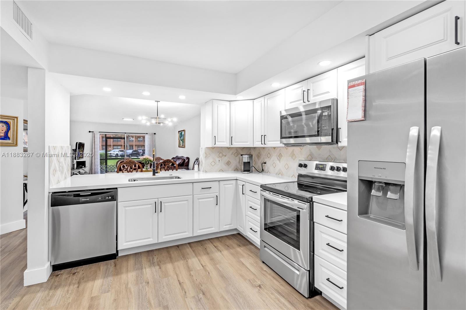 701 Southwest 142nd Avenue, Unit 108S Pembroke Pines, FL 33027 - Photo 2 of 25 a kitchen with stainless steel appliances granite countertop a stove top oven a refrigerator a sink and dishwasher with wooden floor