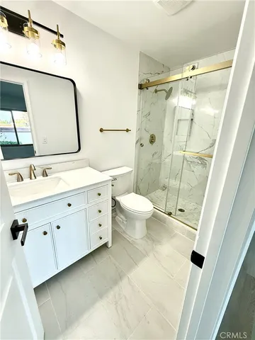 a bathroom with a double vanity sink toilet mirror and shower