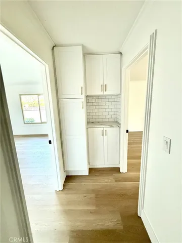 a view of a hallway with wooden floor and a bathroom