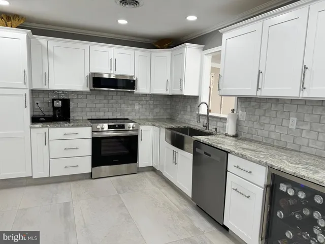 a kitchen with granite countertop white cabinets and stainless steel appliances