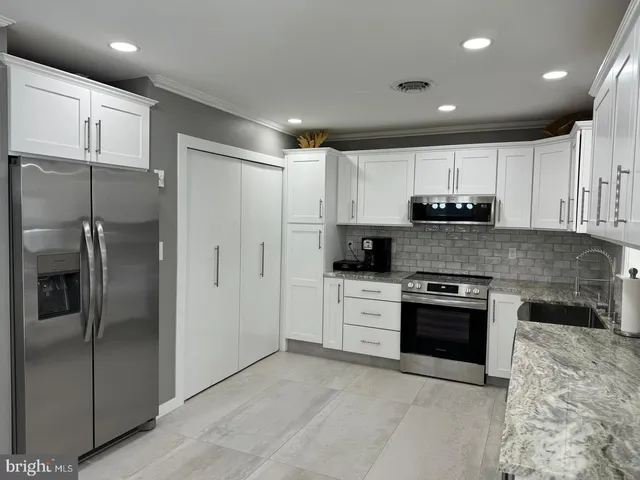a large kitchen with stainless steel appliances granite countertop a refrigerator and a stove top oven