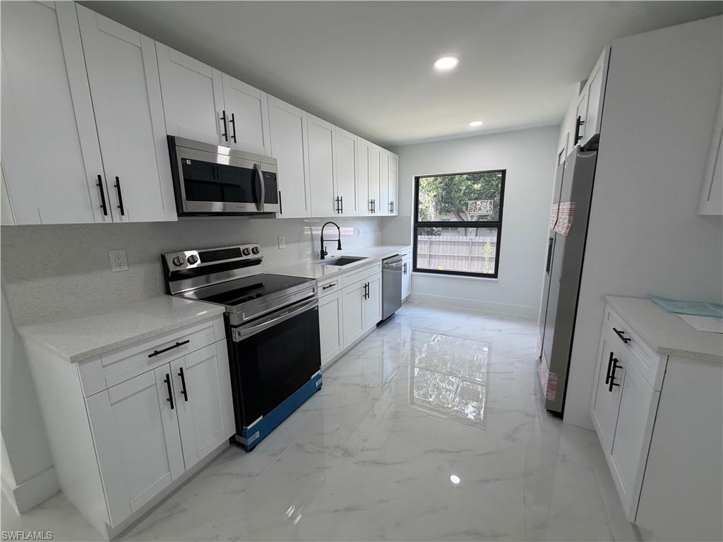 15 Louisiana Road Lehigh Acres, FL 33936 - Photo 5 of 22 a kitchen with white cabinets and black appliances