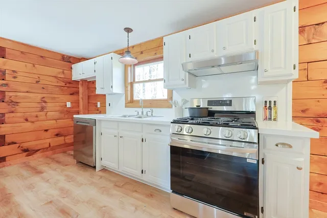 a kitchen with kitchen island granite countertop a sink appliances cabinets and a counter top space