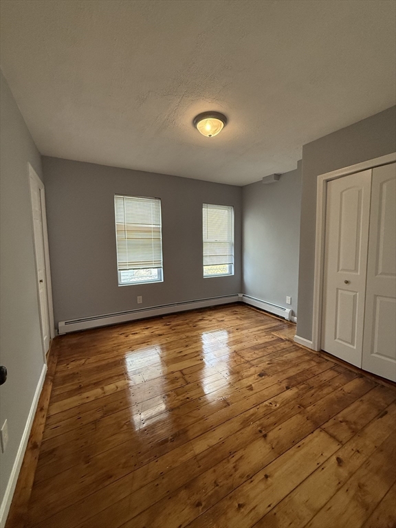 69 Hollis Street, Unit 13 Worcester, MA 01610 - Photo 5 of 8 an empty room with wooden floor and windows