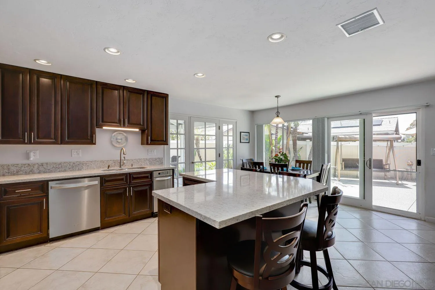 8531 Menkar Road San Diego, CA 92126 - Photo 8 of 37 a large kitchen with granite countertop a stove top oven a sink dishwasher and white cabinets with wooden floor