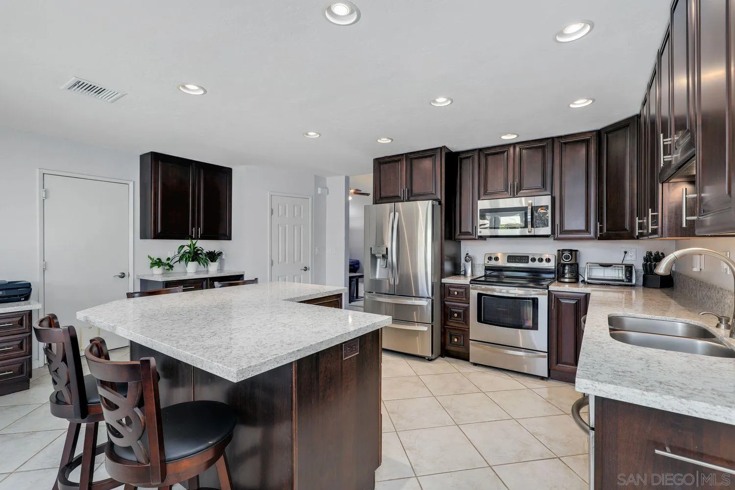 8531 Menkar Road San Diego, CA 92126 - Photo 10 of 37 a kitchen with granite countertop a stove refrigerator and microwave