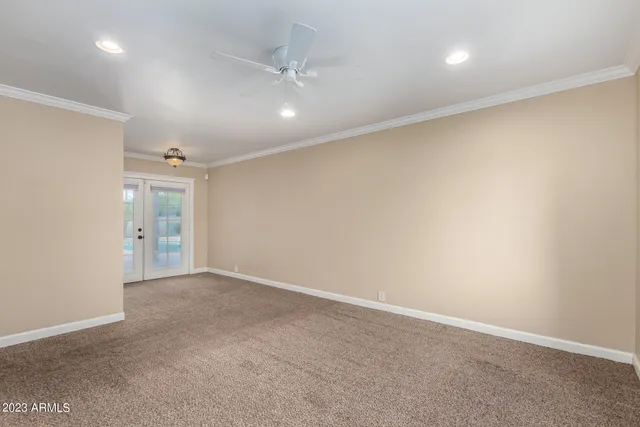 an empty room with fan and hallway
