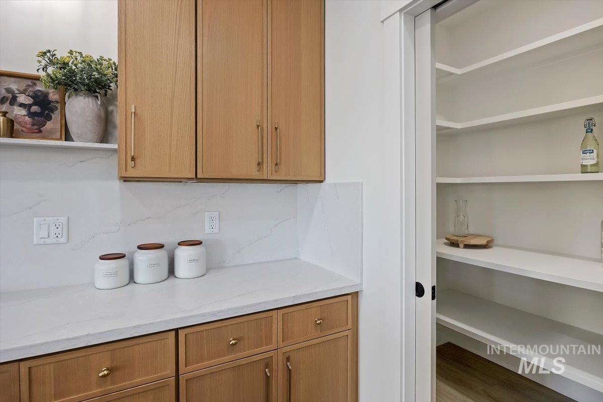 2005 Sparrow Street Rupert, ID 83350 - Photo 12 of 30 Kitchenette featuring natural wood cabinetry with gold-toned hardware, white solid surface countertops, and a full-height solid surface backsplash