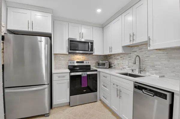 a kitchen with refrigerator a sink and white cabinets