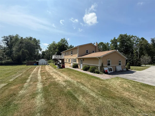 a view of a house with a yard and large trees