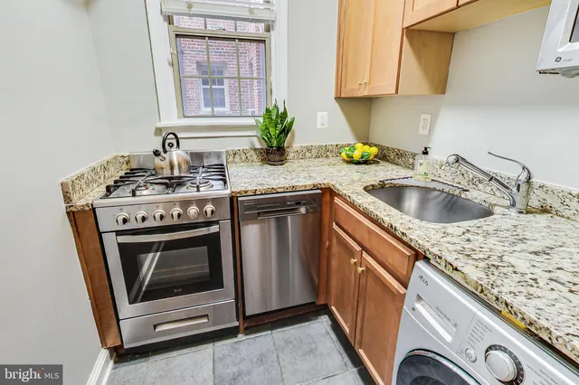 a kitchen with granite countertop a sink stove and cabinets