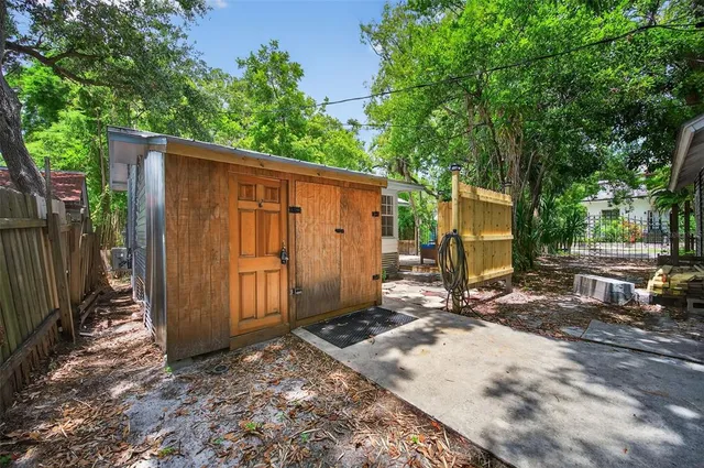 a view of a small yard in front of a house with large trees and plants