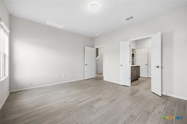 an empty room with wooden floor & windows and bathroom