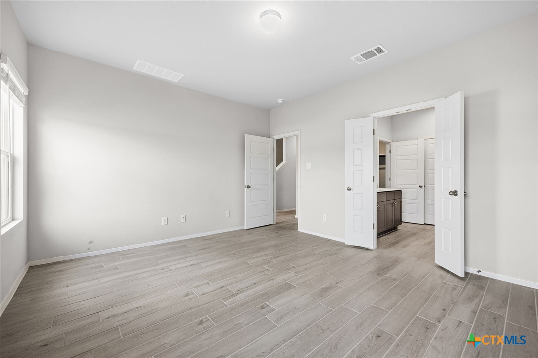 251 Chesterfield Drive Kyle, TX 78640 - Photo 12 of 24 an empty room with wooden floor & windows and bathroom