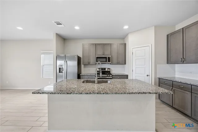 a kitchen with stainless steel appliances granite countertop a sink a stove a refrigerator a microwave and island