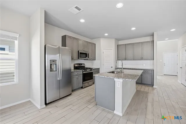 a kitchen with stainless steel appliances a sink stove refrigerator and cabinets