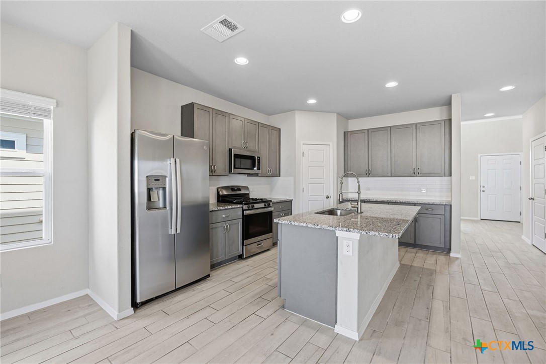 251 Chesterfield Drive Kyle, TX 78640 - Photo 8 of 24 a kitchen with stainless steel appliances a sink stove refrigerator and cabinets