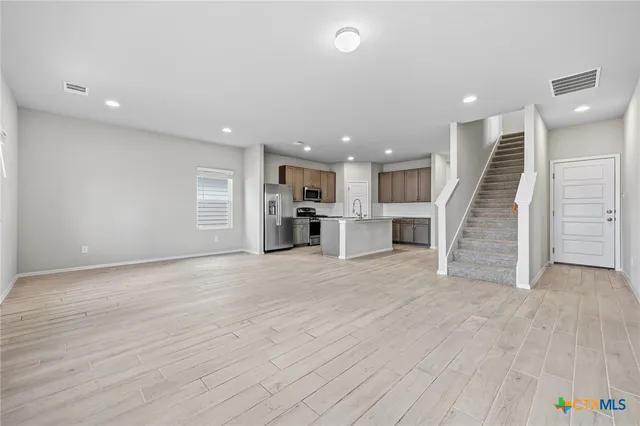 a view of a big room with entryway wooden floor and kitchen view