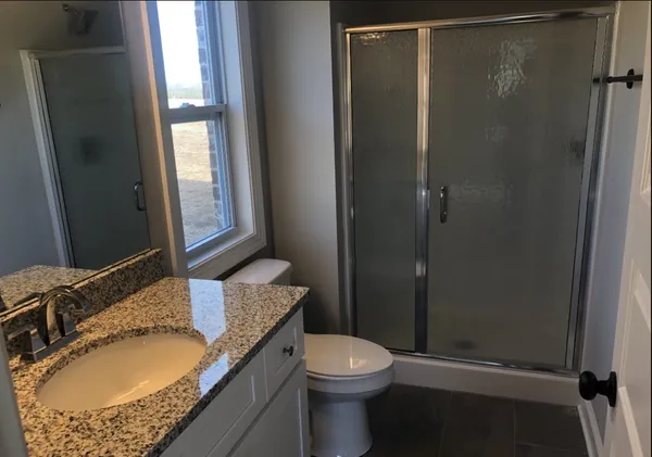 a bathroom with a granite countertop sink toilet and shower
