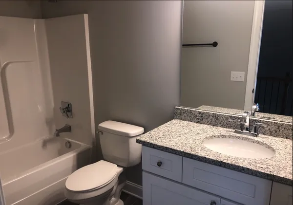 a bathroom with a granite countertop toilet a sink and a bathtub