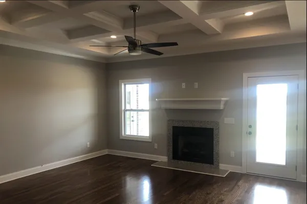 an empty room with wooden floor fireplace and windows