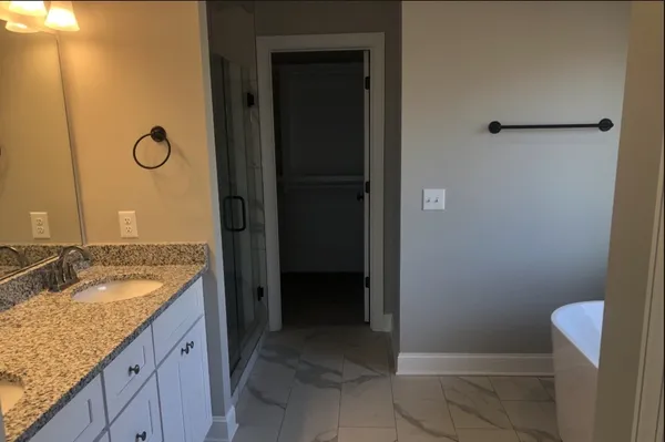 a bathroom with a granite countertop sink a mirror and shower