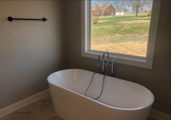 a white bath tub sitting in a bathroom next to a window
