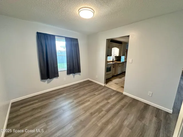an empty room with wooden floor and mirror