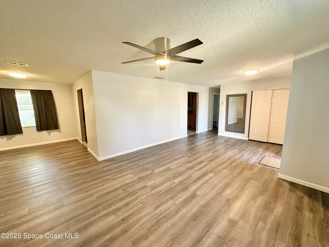 a view of a livingroom with wooden floor and a ceiling fan