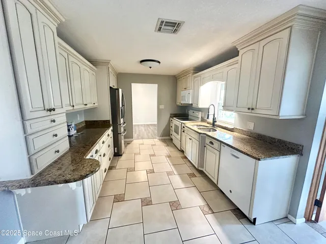 a large kitchen with a stove a sink dishwasher and a refrigerator