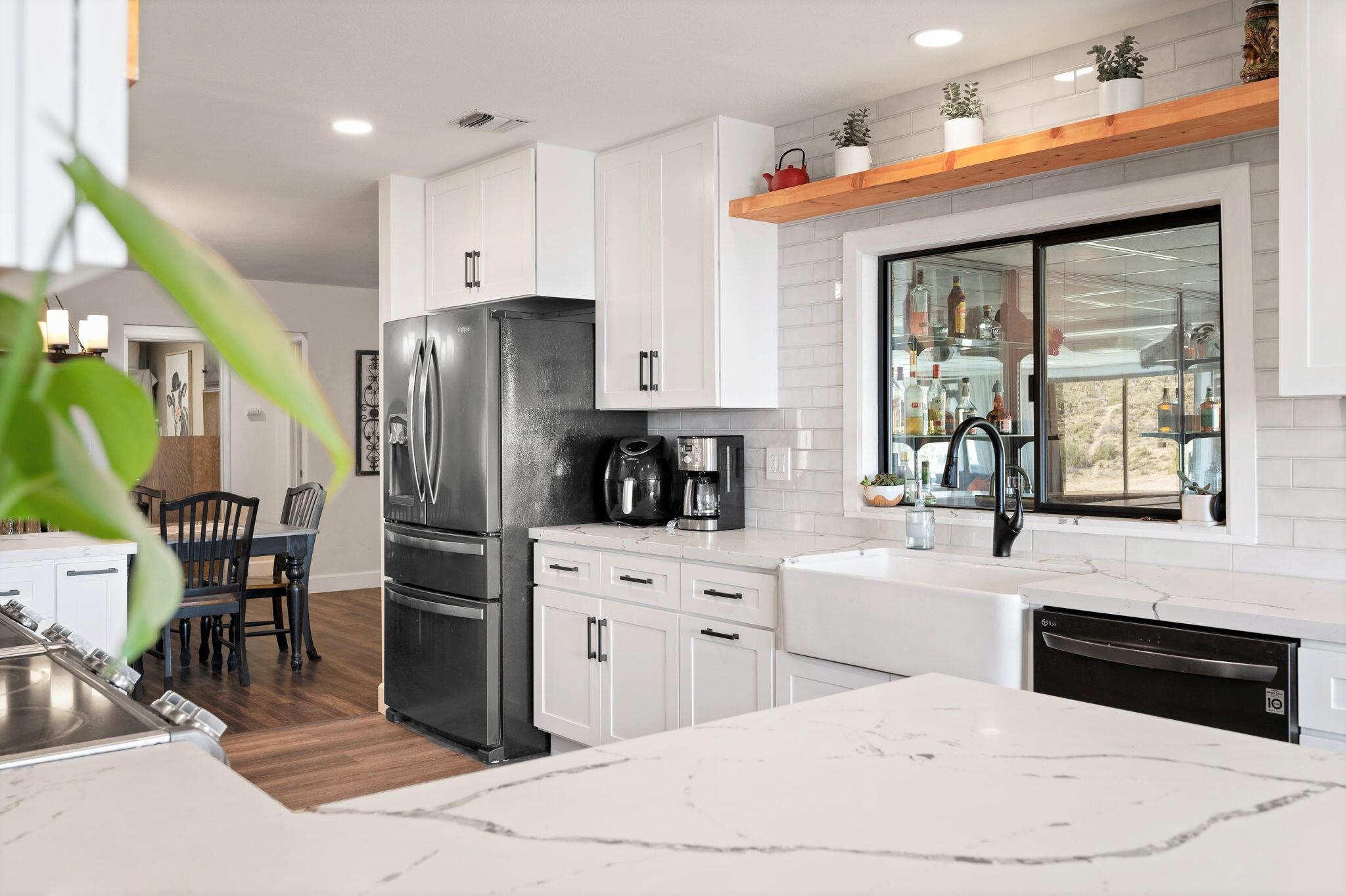 53988 Pinon Drive Yucca Valley, CA 92284 - Photo 10 of 42 a kitchen with stainless steel appliances a refrigerator a stove a sink a dining table and chairs with wooden floor