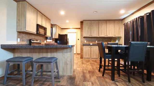 a kitchen with stainless steel appliances granite countertop a table chairs sink and cabinets