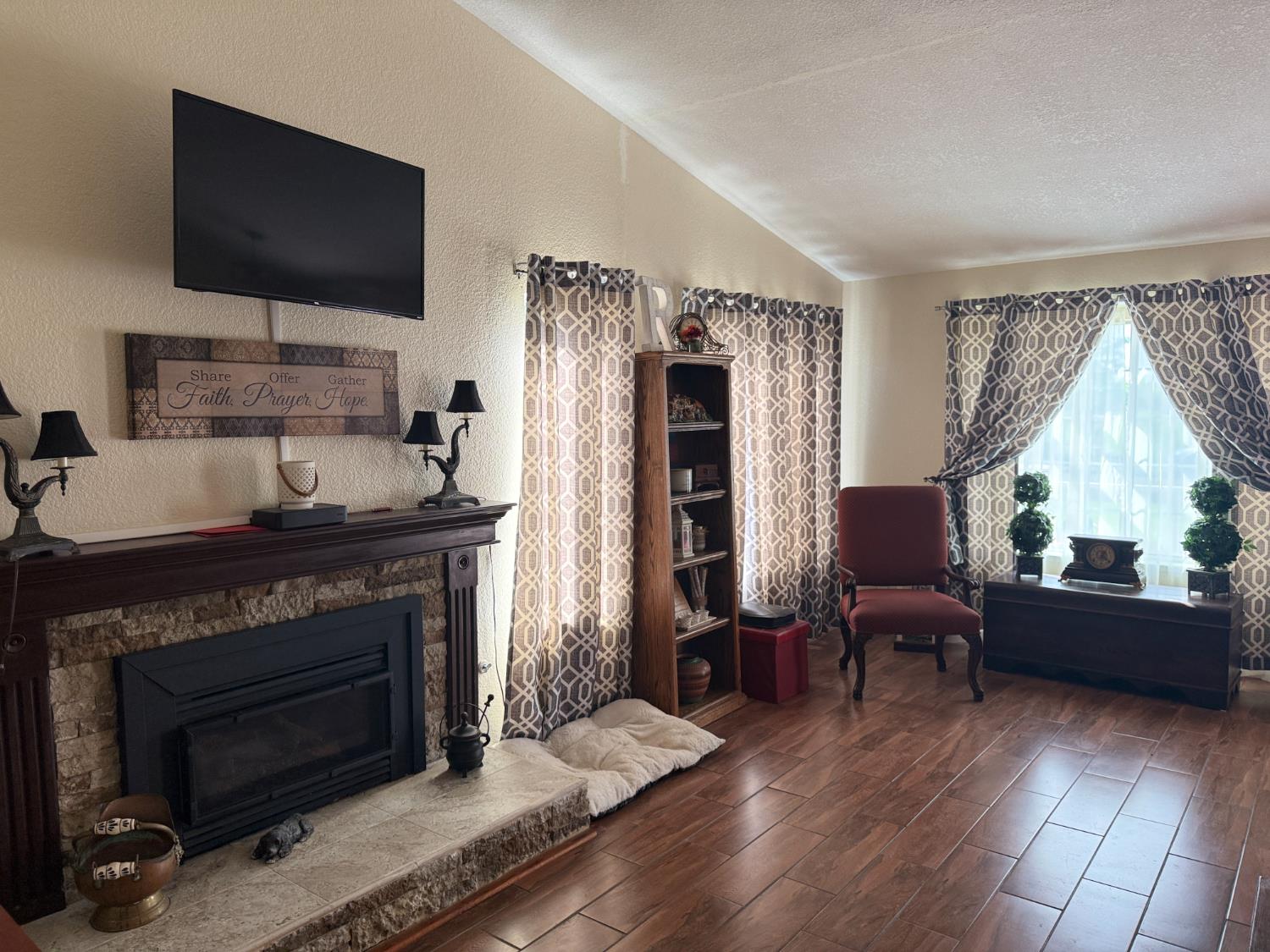 14312 West B Street Kerman, CA 93630 - Photo 4 of 24 a living room with furniture a flat screen tv and a fireplace