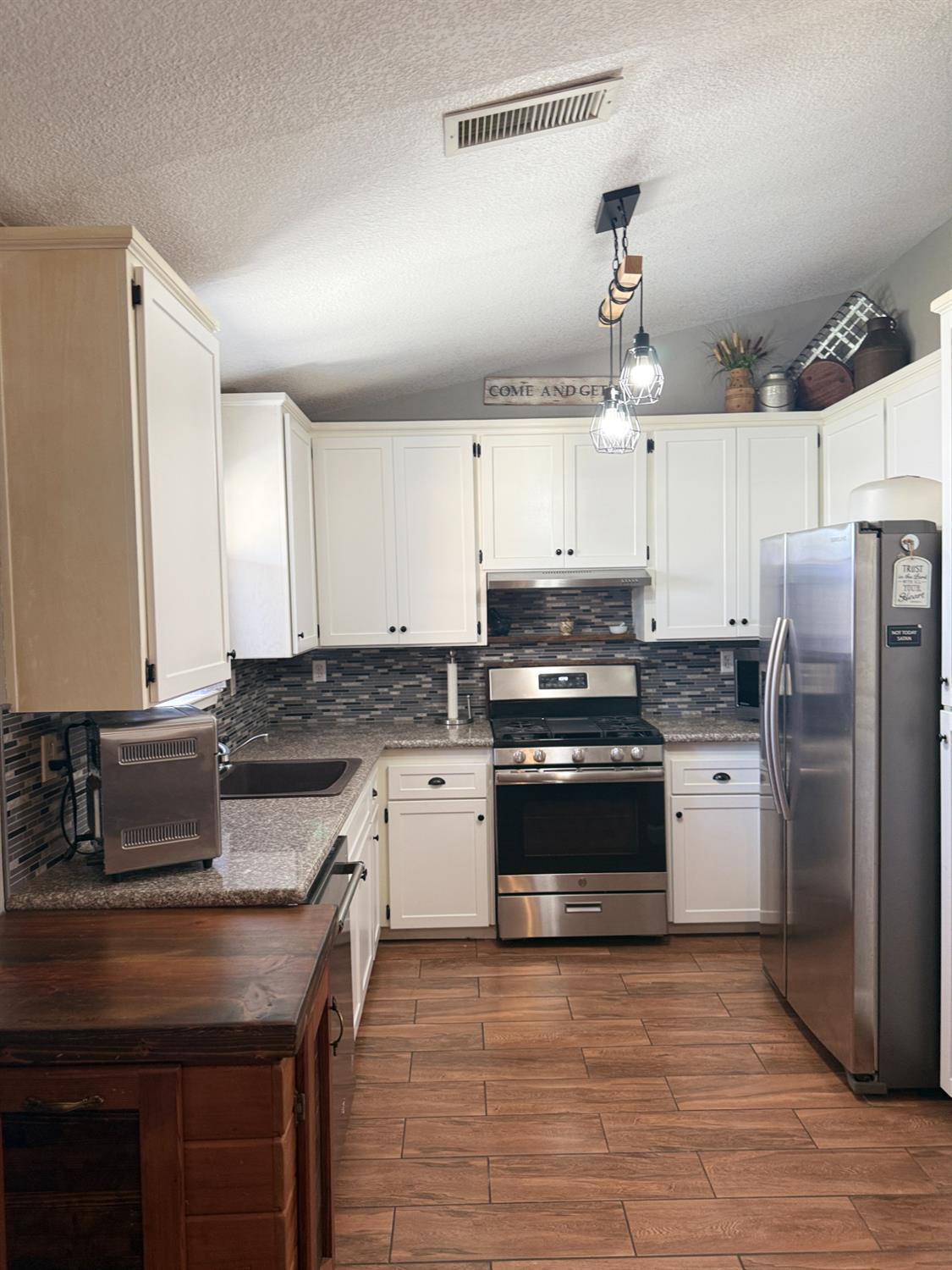 14312 West B Street Kerman, CA 93630 - Photo 5 of 24 a kitchen with stainless steel appliances granite countertop a stove refrigerator sink and microwave
