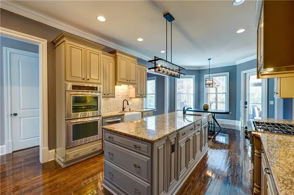 a kitchen with a stove a sink a refrigerator and chairs