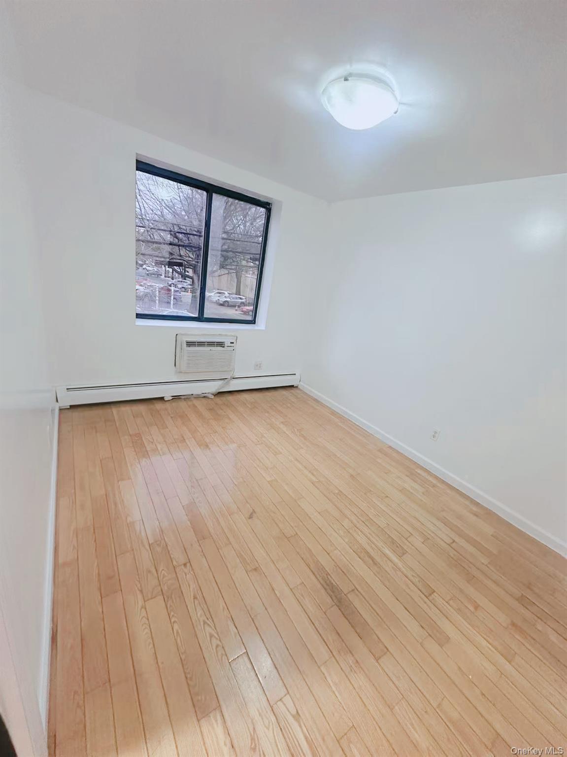 136-16 35th Avenue, Unit 2B Queens, NY 11354 - Photo 2 of 8 an empty room with wooden floor and windows