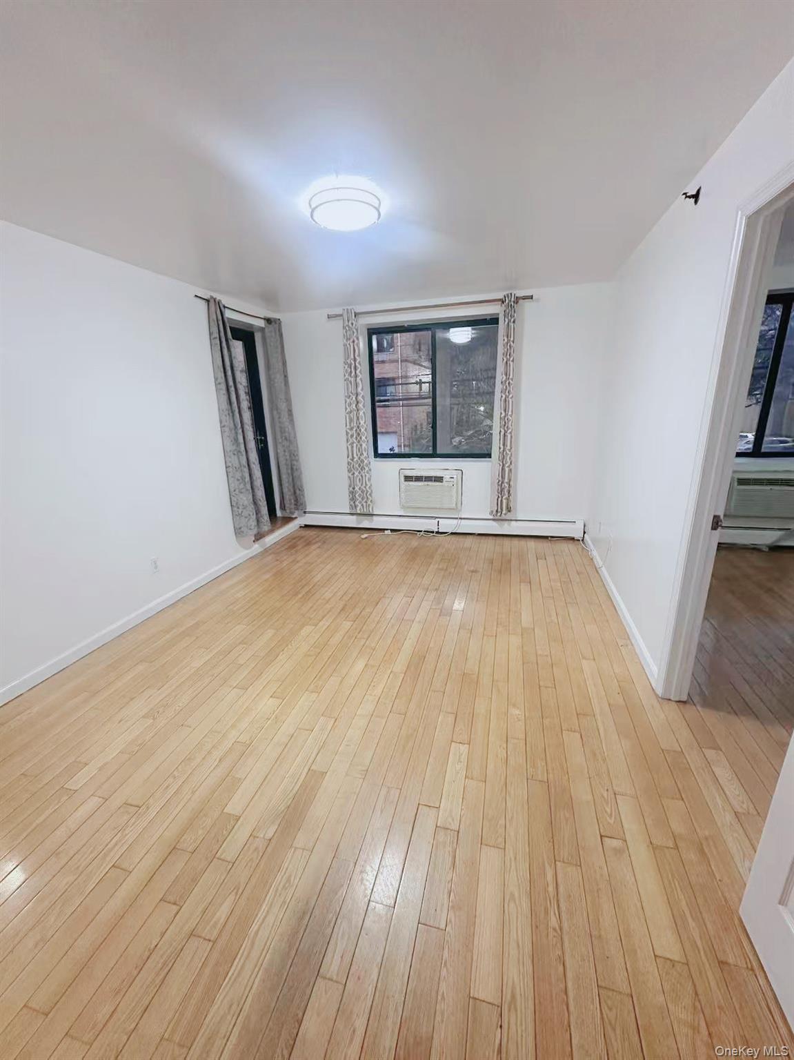 136-16 35th Avenue, Unit 2B Queens, NY 11354 - Photo 4 of 8 wooden floor in an empty room with a window