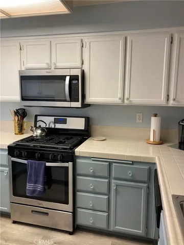 a kitchen with granite countertop white cabinets and stainless steel appliances