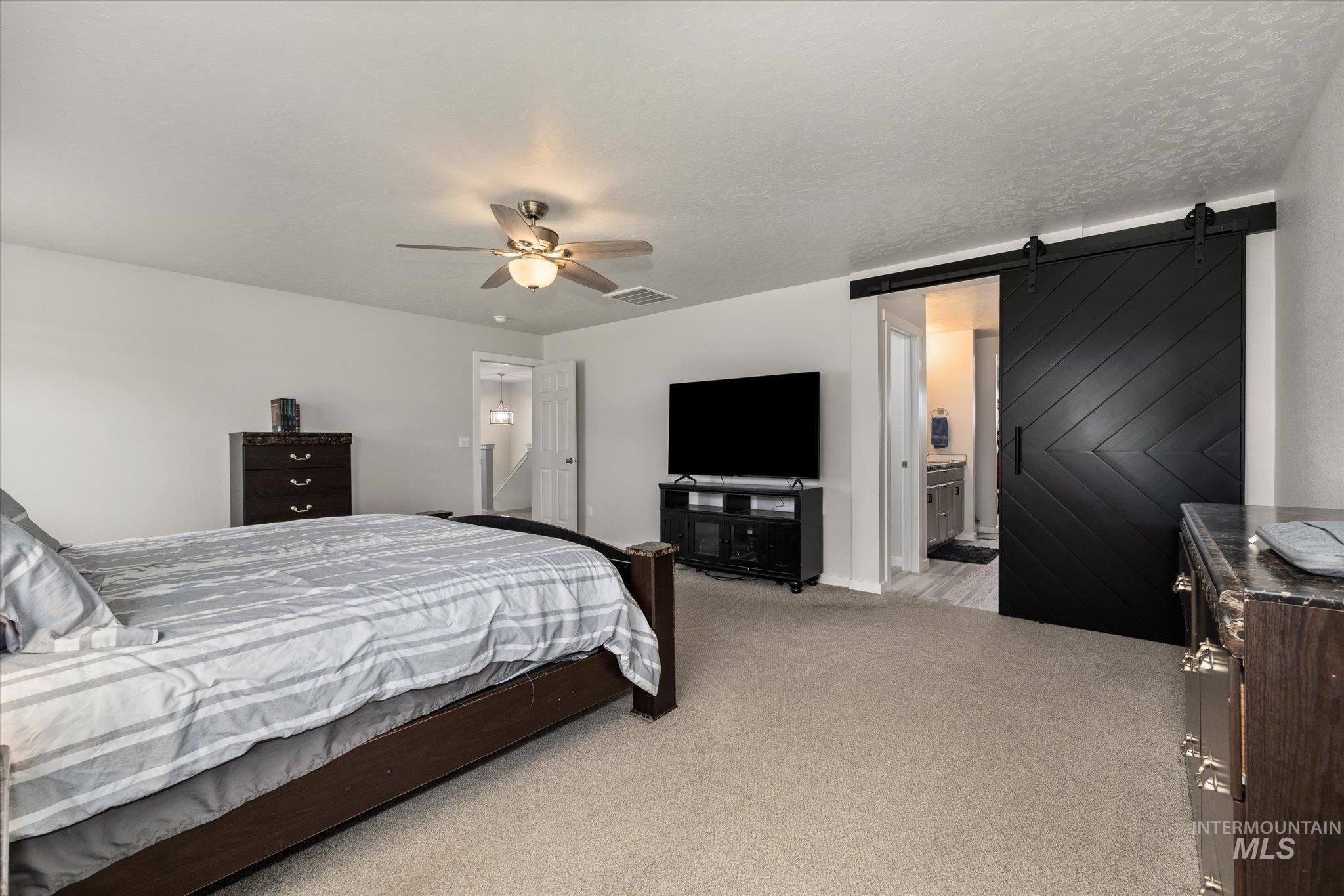 2024 Placerville Street Middleton, ID 83644 - Photo 18 of 38 Bedroom featuring a barn door, light colored carpet, ceiling fan, and ensuite bathroom