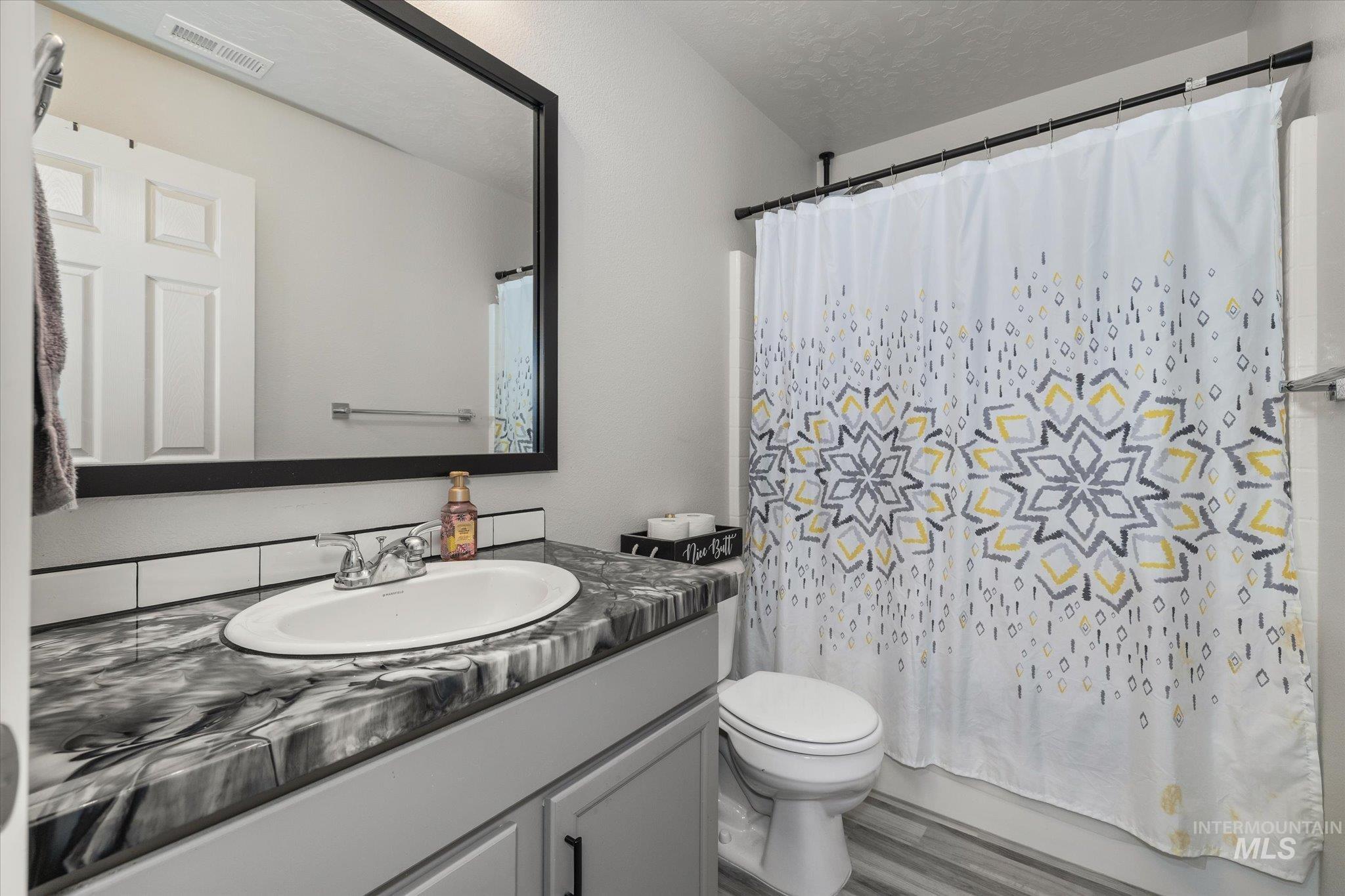 2024 Placerville Street Middleton, ID 83644 - Photo 29 of 38 Full bathroom with vanity, shower / bath combo, a textured ceiling, and wood finished floors