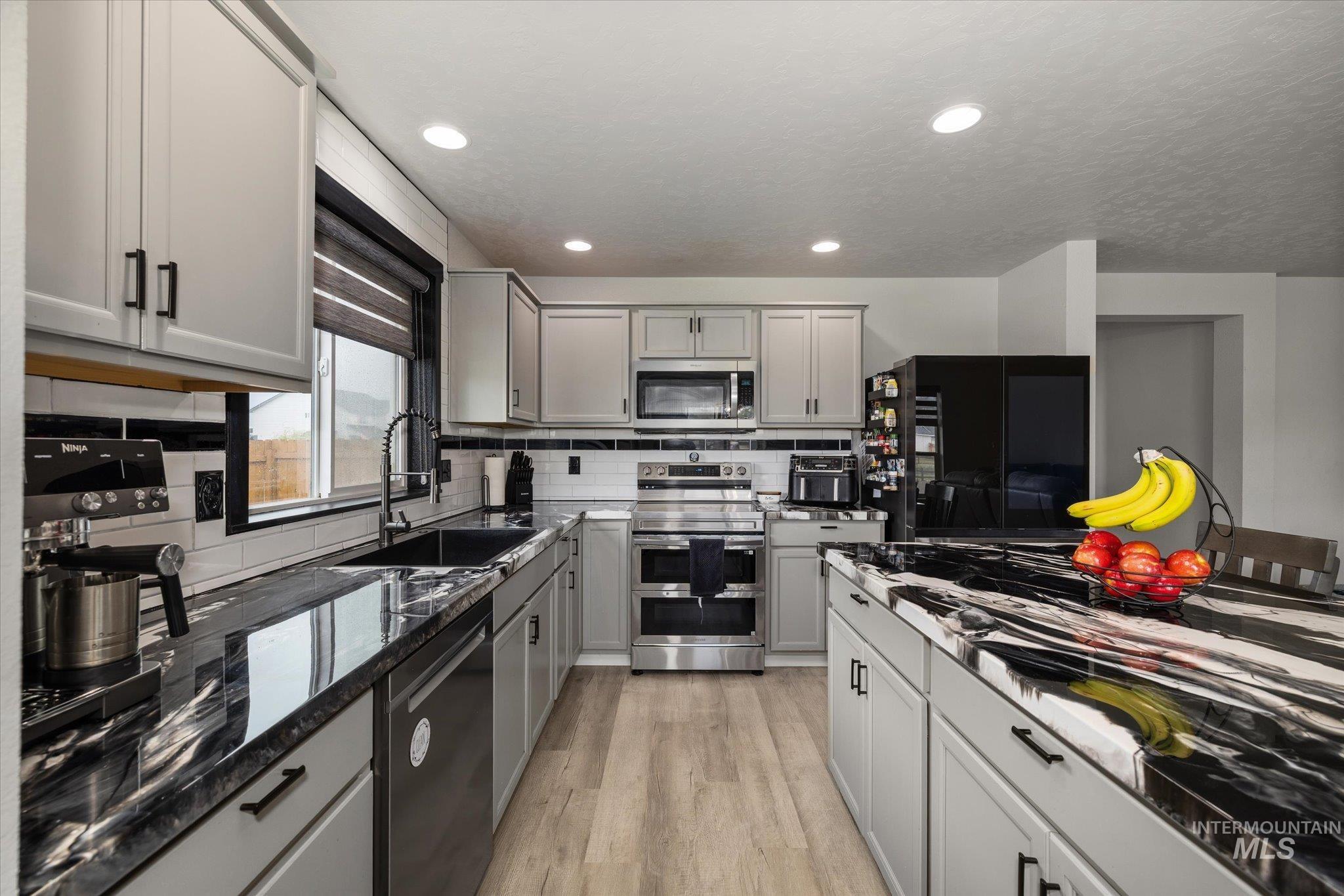 2024 Placerville Street Middleton, ID 83644 - Photo 3 of 38 Kitchen featuring stainless steel appliances, gray cabinetry, light wood-style flooring, dark stone countertops, and recessed lighting