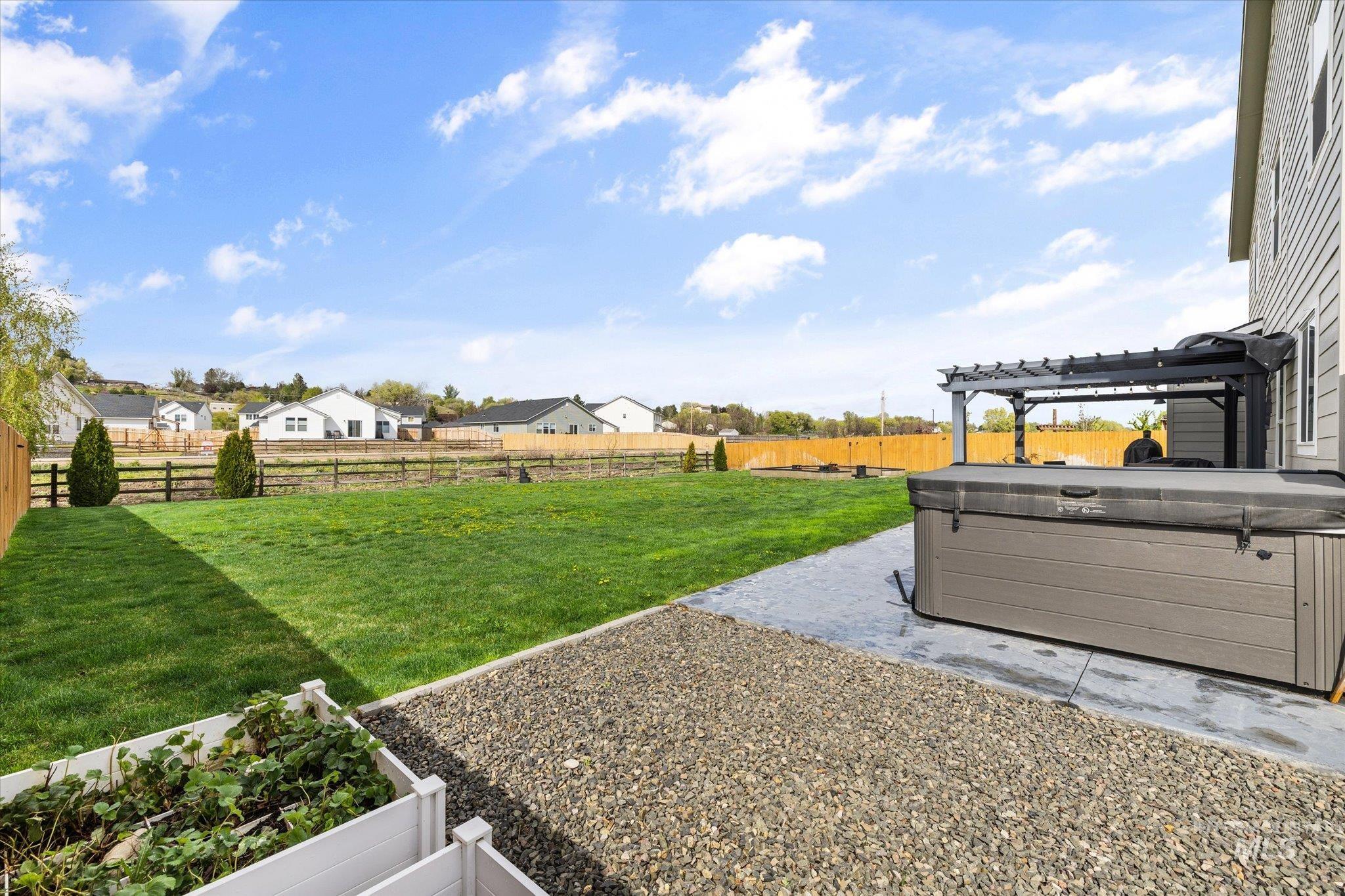 2024 Placerville Street Middleton, ID 83644 - Photo 34 of 38 Fenced backyard with a patio area, a hot tub, a vegetable garden, a residential view, and a pergola