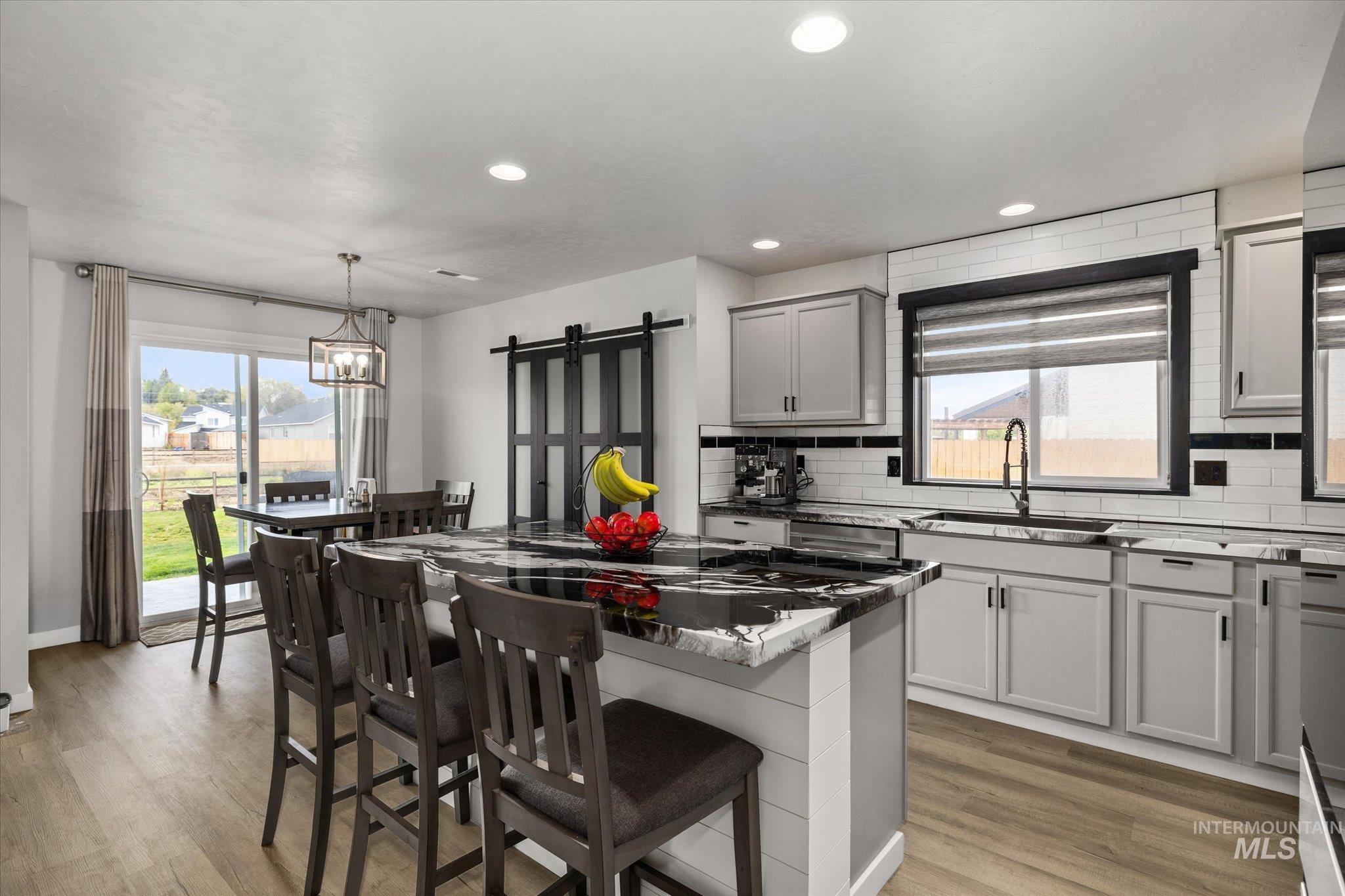2024 Placerville Street Middleton, ID 83644 - Photo 6 of 38 Kitchen with tasteful backsplash, gray cabinetry, a center island, a barn door, and dark stone countertops