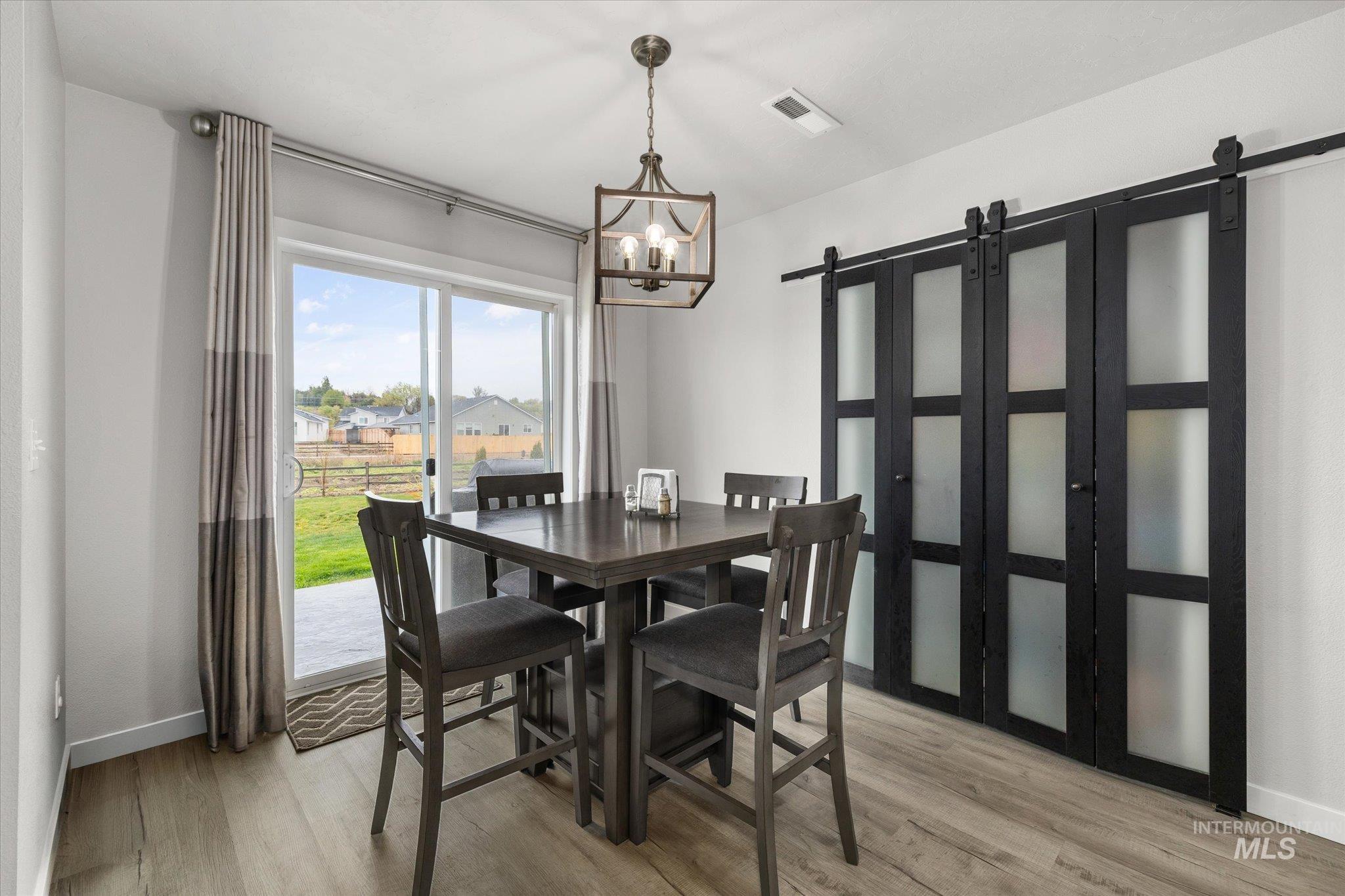 2024 Placerville Street Middleton, ID 83644 - Photo 7 of 38 Dining space featuring a barn door, light wood-style flooring, and suspended lighting