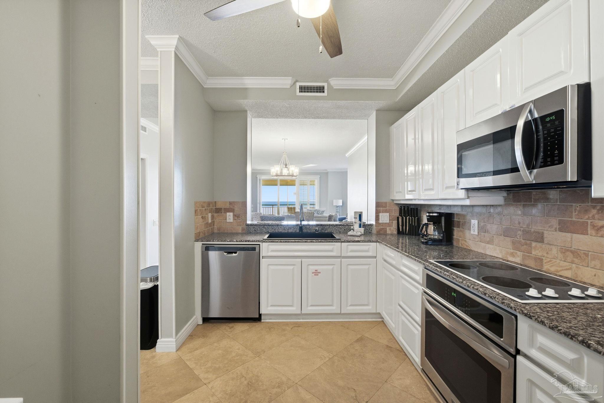 13601 Perdido Key Drive, Unit W2C Perdido Key, FL 32507 - Photo 27 of 63 a kitchen with stainless steel appliances granite countertop a stove top oven a sink and dishwasher